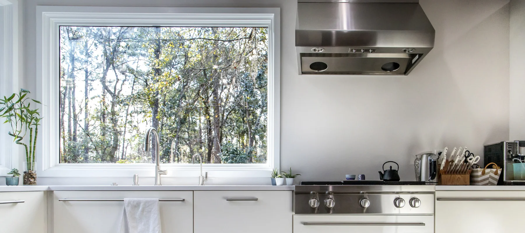 Bright kitchen with a large picture window over the sink offering a view of a wooded backyard
