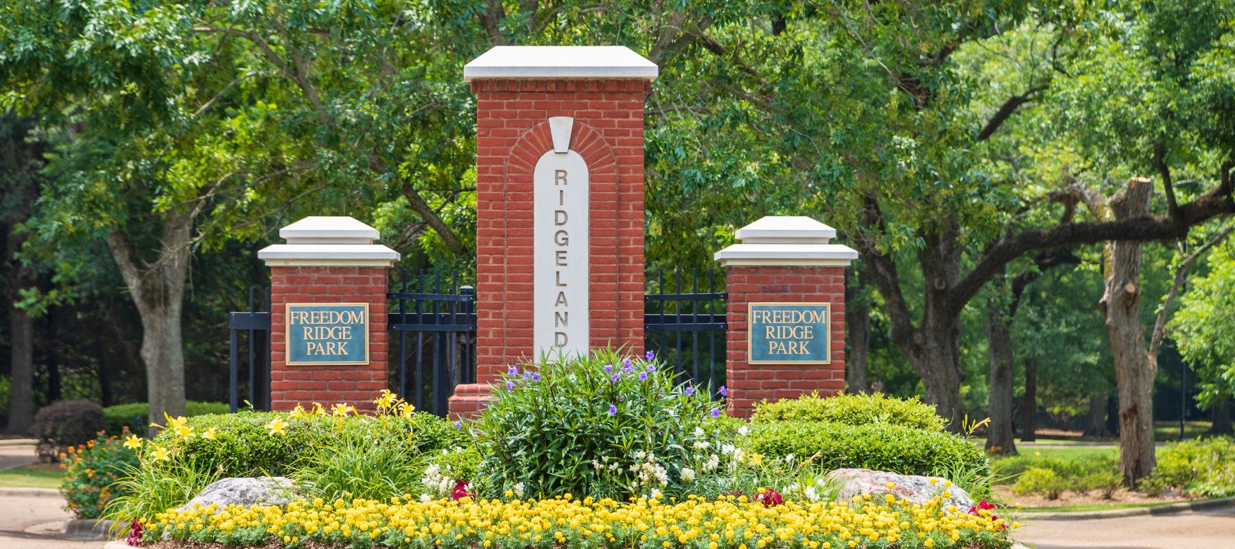 Red brick entrance sign for Ridgeland's Freedom Ridge Park surrounded by colorful flower beds